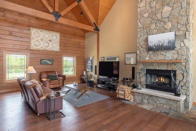 12000 Ute Pass Rd, Parshall, CO 80468 - living area with high vaulted ceiling, a stone fireplace, hardwood / wood-style flooring, wooden ceiling with exposed beams, and wooden walls