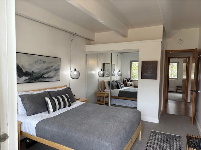 bedroom with a closet, beam ceiling, carpet flooring, baseboard heating, and baseboards