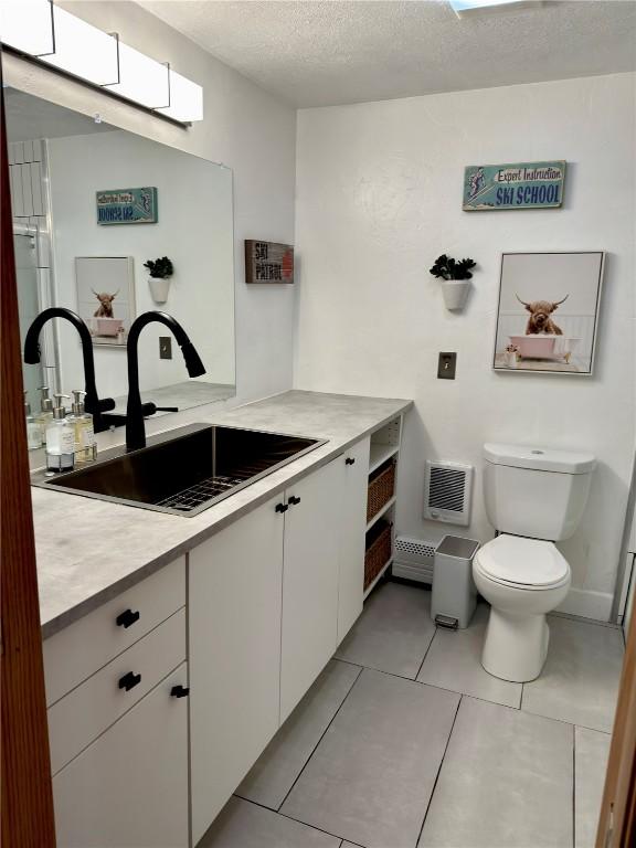 bathroom with toilet, tile patterned flooring, vanity, and a textured ceiling