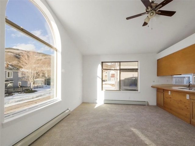 unfurnished living room featuring lofted ceiling, a baseboard heating unit, light carpet, and ceiling fan