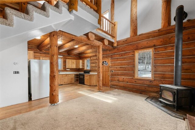 57785 Saturn Ct, Clark, CO 80428 - unfurnished living room featuring light carpet, a high ceiling, rustic walls, and a wood stove