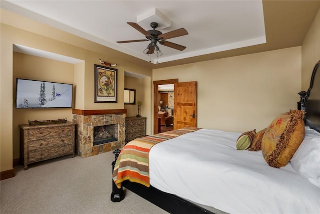 bedroom with ceiling fan, carpet flooring, and a stone fireplace