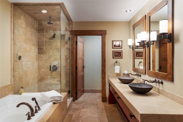full bath featuring a sink, double vanity, recessed lighting, a garden tub, and a stall shower