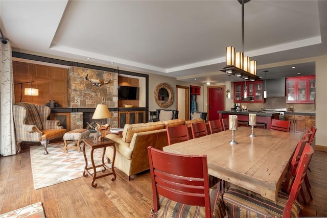 dining space with wood finished floors and a raised ceiling