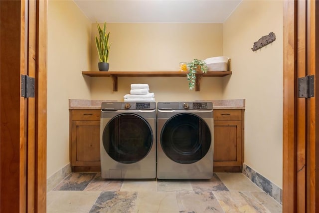 washroom featuring separate washer and dryer, stone finish flooring, cabinet space, and baseboards