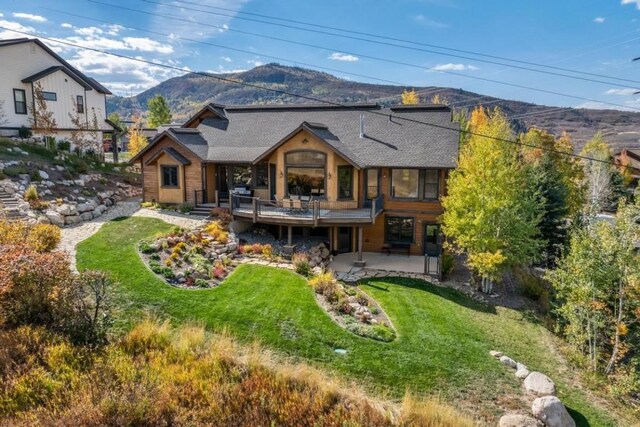 1138 Longview Cir, Steamboat Springs, CO 80487 - back of house with a mountain view, a patio, a lawn, and roof with shingles