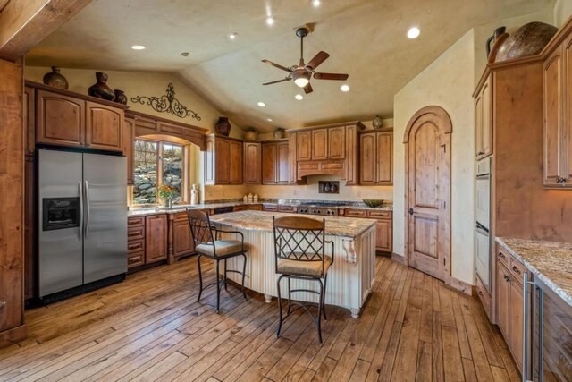 1138 Longview Cir, Steamboat Springs, CO 80487 - kitchen featuring appliances with stainless steel finishes, vaulted ceiling, a ceiling fan, a center island, and light wood-style floors