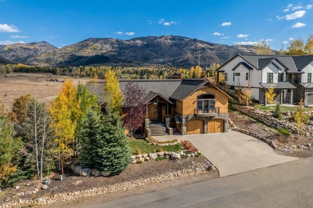 1138 Longview Cir, Steamboat Springs, CO 80487 - view of front facade with stone siding, a garage, concrete driveway, and a mountain view