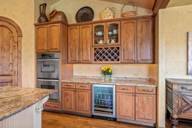 1138 Longview Cir, Steamboat Springs, CO 80487 - kitchen featuring double oven, wine cooler, light stone counters, lofted ceiling, and light wood-style floors