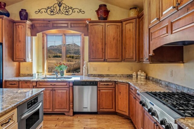 1138 Longview Cir, Steamboat Springs, CO 80487 - kitchen with appliances with stainless steel finishes, lofted ceiling, light wood-style floors, light stone counters, and a sink