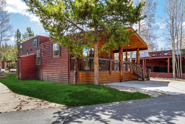 view of side of property featuring a lawn, faux log siding, and a porch
