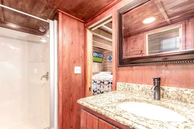 bathroom featuring a stall shower, vanity, ensuite bath, and wooden walls
