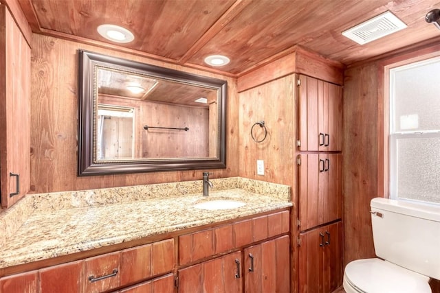 bathroom featuring toilet, vanity, wooden walls, and wood ceiling