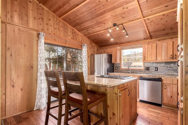 kitchen featuring appliances with stainless steel finishes, vaulted ceiling, light wood-style flooring, wooden ceiling, and light brown cabinetry