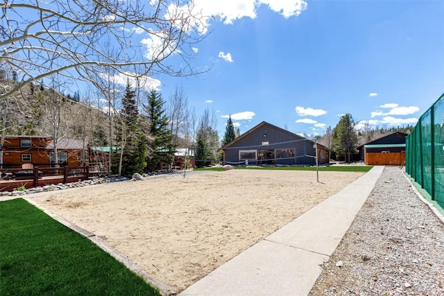 view of home's community with volleyball court and fence