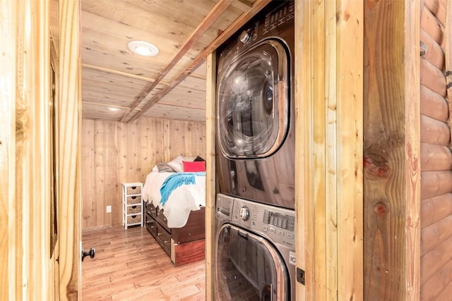 laundry area featuring stacked washer and clothes dryer, wooden ceiling, hardwood / wood-style flooring, and wood walls