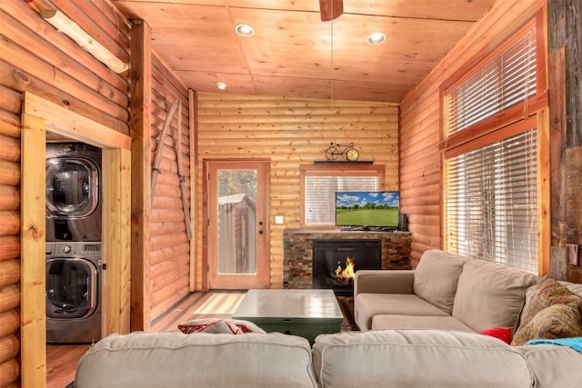 living room with stacked washer / dryer, rustic walls, wooden ceiling, a fireplace, and wood finished floors