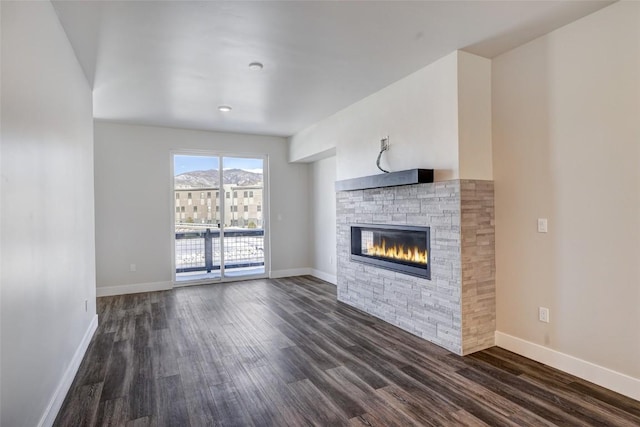 unfurnished living room featuring baseboards, dark wood-type flooring, and a fireplace
