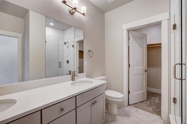 bathroom featuring a shower stall, a sink, a walk in closet, double vanity, and toilet