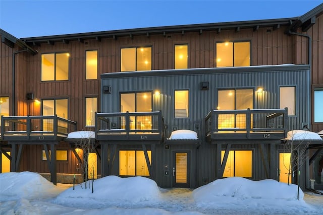 snow covered rear of property featuring a balcony