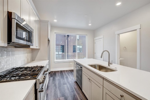 kitchen featuring tasteful backsplash, a sink, stainless steel appliances, light countertops, and dark wood-style floors