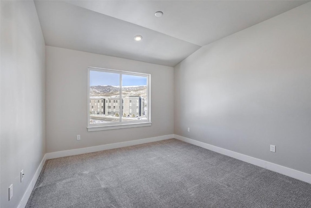carpeted spare room featuring recessed lighting, vaulted ceiling, and baseboards