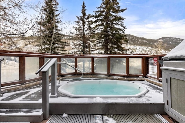 snow covered deck featuring an outdoor hot tub and a mountain view