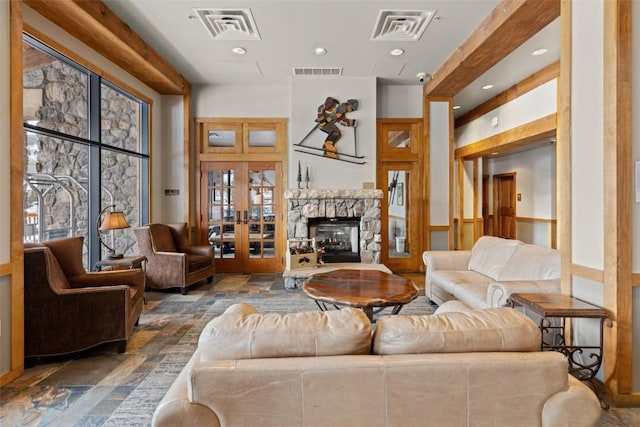 living area featuring stone tile floors, visible vents, and french doors