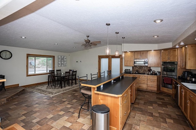 420 County Road 64, Craig, CO 81625 - kitchen with stainless steel appliances, a textured ceiling, stone finish floor, a kitchen island, and dark countertops