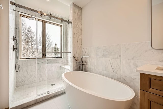 bathroom featuring shower with separate bathtub, tile walls, vanity, and tile patterned floors