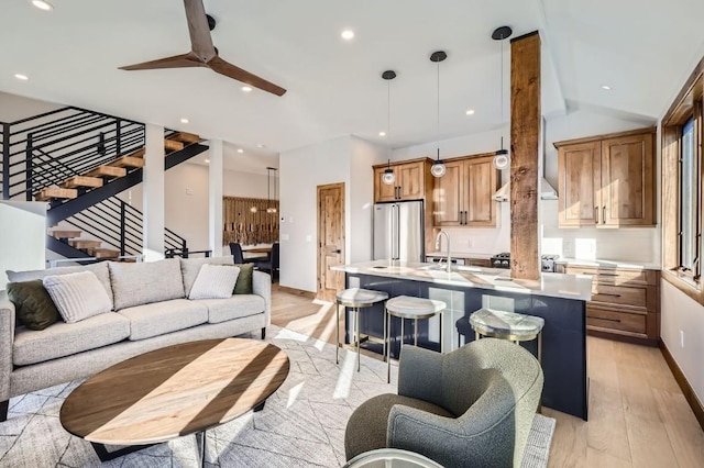 living room with ceiling fan, sink, and light wood-type flooring