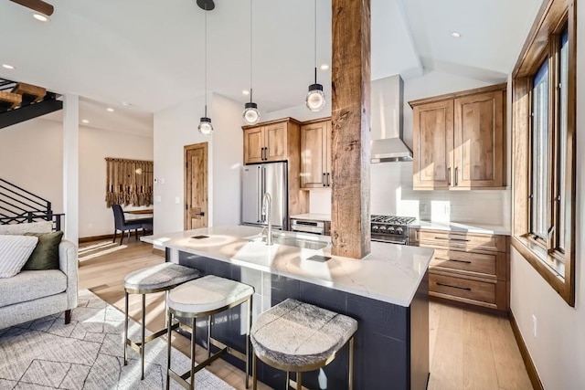 kitchen with pendant lighting, wall chimney range hood, backsplash, high quality appliances, and a kitchen bar