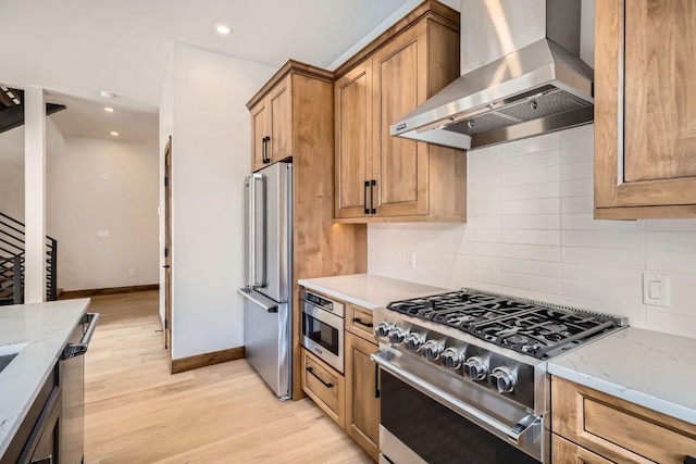 kitchen featuring backsplash, exhaust hood, light hardwood / wood-style floors, stainless steel appliances, and light stone countertops