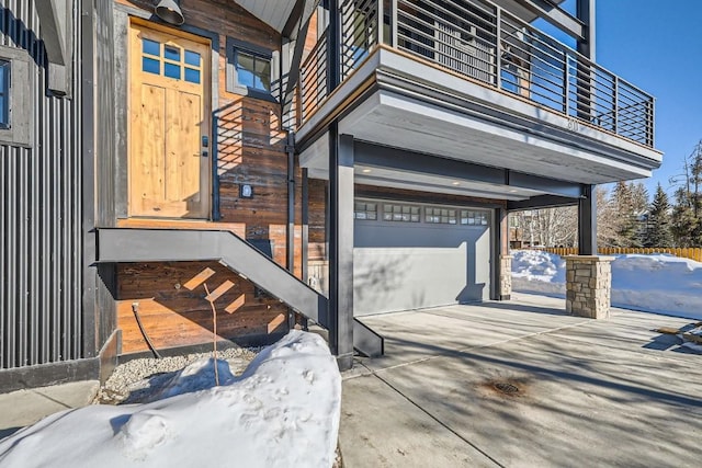 snow covered patio with a garage and a balcony