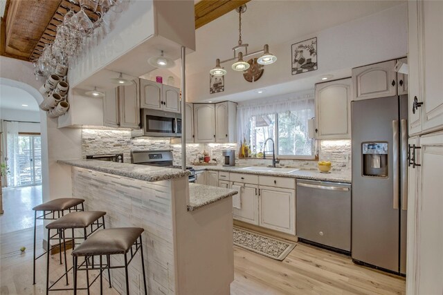 14 Rock Springs Rd, Breckenridge, CO 80424 - kitchen featuring stainless steel appliances, a sink, a kitchen breakfast bar, light wood-style floors, and backsplash