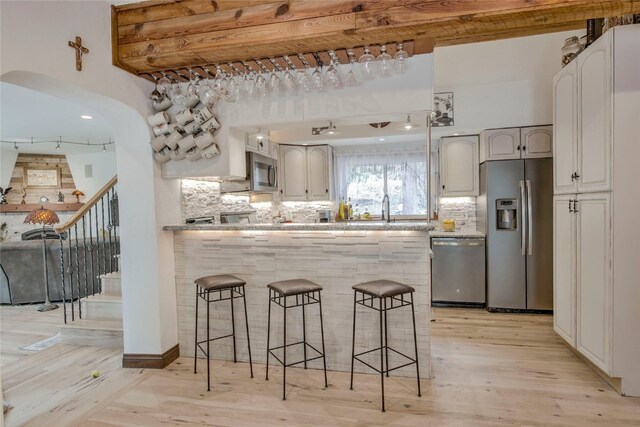14 Rock Springs Rd, Breckenridge, CO 80424 - kitchen with appliances with stainless steel finishes, a kitchen bar, light wood finished floors, and decorative backsplash