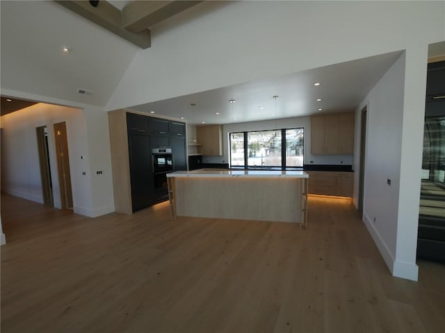 kitchen with light wood-type flooring, beam ceiling, a center island, and high vaulted ceiling