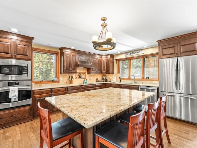 50 Sunset Dr, Breckenridge, CO 80424 - kitchen featuring appliances with stainless steel finishes, light wood finished floors, light stone countertops, a kitchen breakfast bar, and recessed lighting