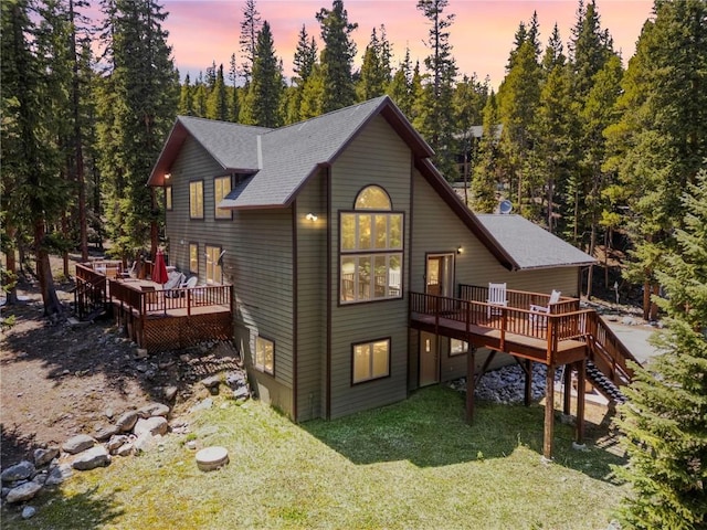 50 Sunset Dr, Breckenridge, CO 80424 - back of house at dusk featuring a wooden deck, a lawn, stairs, a shingled roof, and view of wooded area