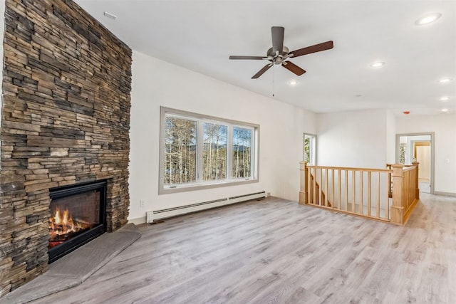 unfurnished living room featuring baseboard heating, ceiling fan, a fireplace, and light hardwood / wood-style flooring