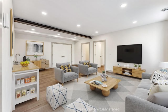 living room featuring beam ceiling and light hardwood / wood-style floors