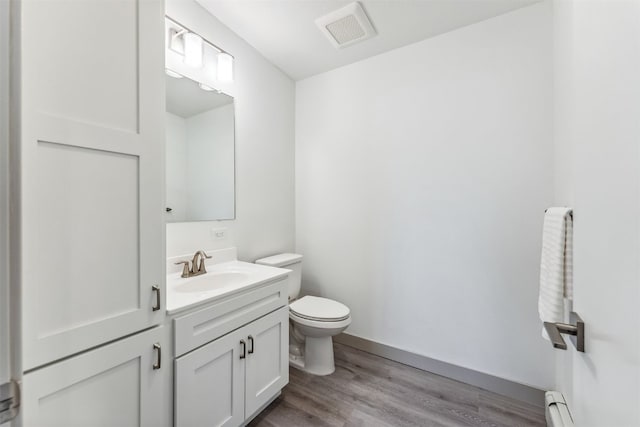 bathroom featuring hardwood / wood-style floors, vanity, toilet, and a baseboard heating unit