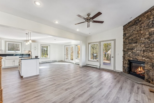 unfurnished living room featuring baseboard heating, a fireplace, and light hardwood / wood-style floors