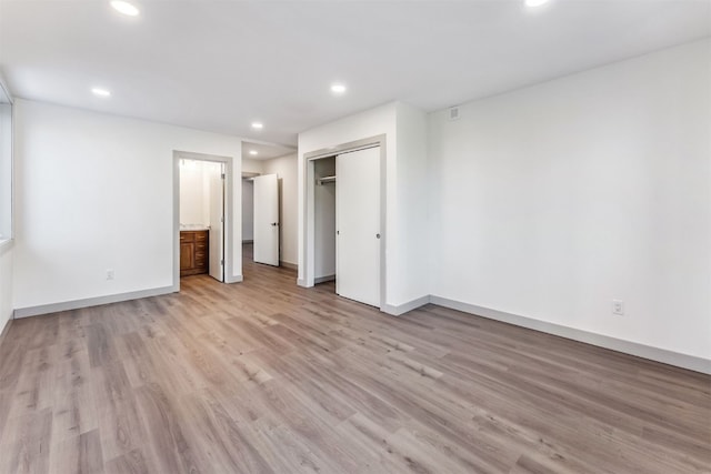 unfurnished bedroom featuring a closet, light hardwood / wood-style flooring, and ensuite bath