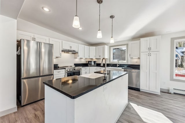 kitchen featuring pendant lighting, vaulted ceiling, a kitchen island, white cabinetry, and stainless steel appliances