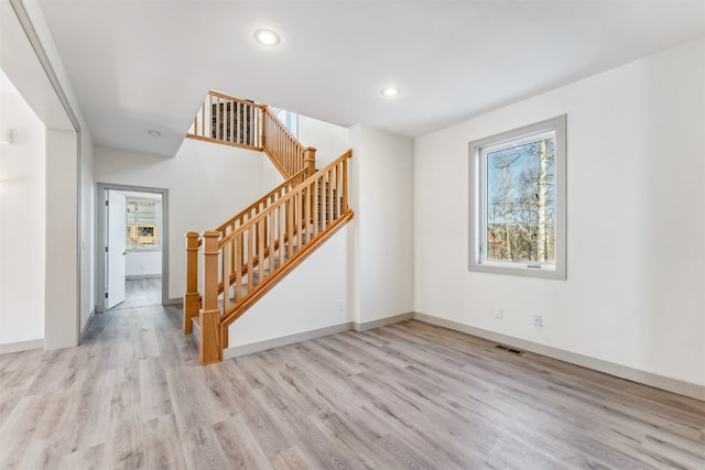 unfurnished living room featuring a wealth of natural light and light hardwood / wood-style floors