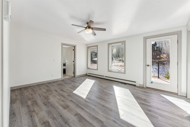 empty room featuring baseboard heating, ceiling fan, and light hardwood / wood-style floors