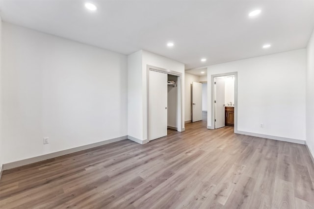 unfurnished bedroom with connected bathroom, a closet, and light hardwood / wood-style floors