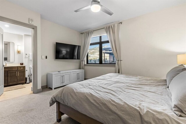 bedroom with ceiling fan, connected bathroom, and light colored carpet