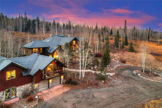 348 Jade Rd, Silverthorne, CO 80498 - view of front facade with a shingled roof, an attached garage, asphalt driveway, stone siding, and a forest view